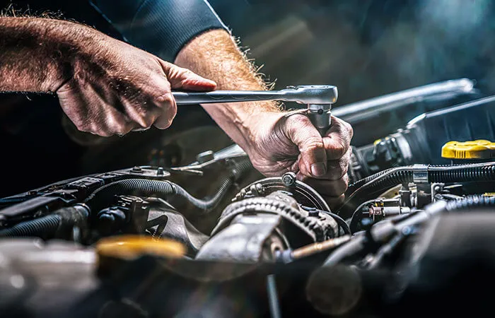 Mechanic using wrench on car engine
