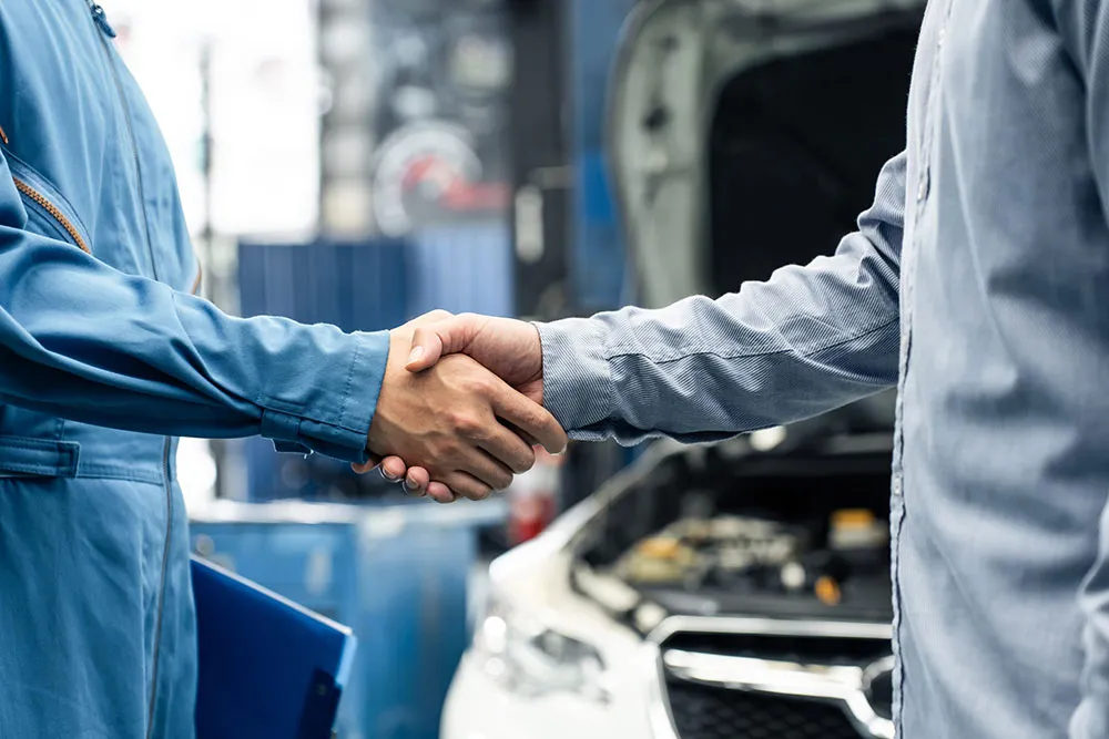 Mechanic and customer handshake at car service.